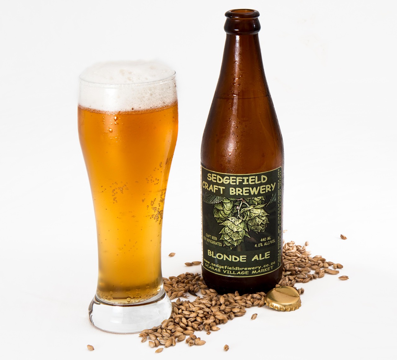 Craft beer bottle and glass with malted barley grains showing the final product of temperature-controlled fermentation