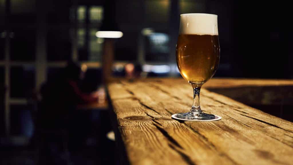 Glass of craft beer on a wooden bar counter showing the end result of temperature-controlled fermentation
