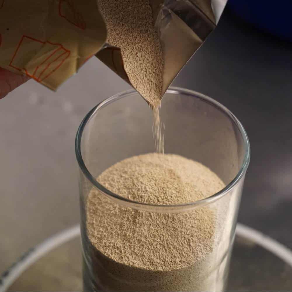 Pouring bag of yeast into glass container